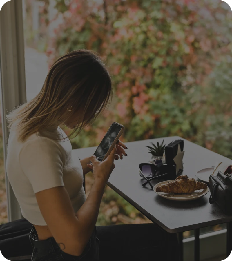 Woman using phone at cafe table