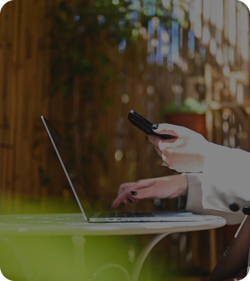 Person using laptop and phone outdoors