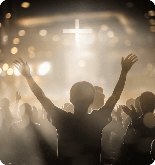 Person raising hands in worship with a bright cross in the background.