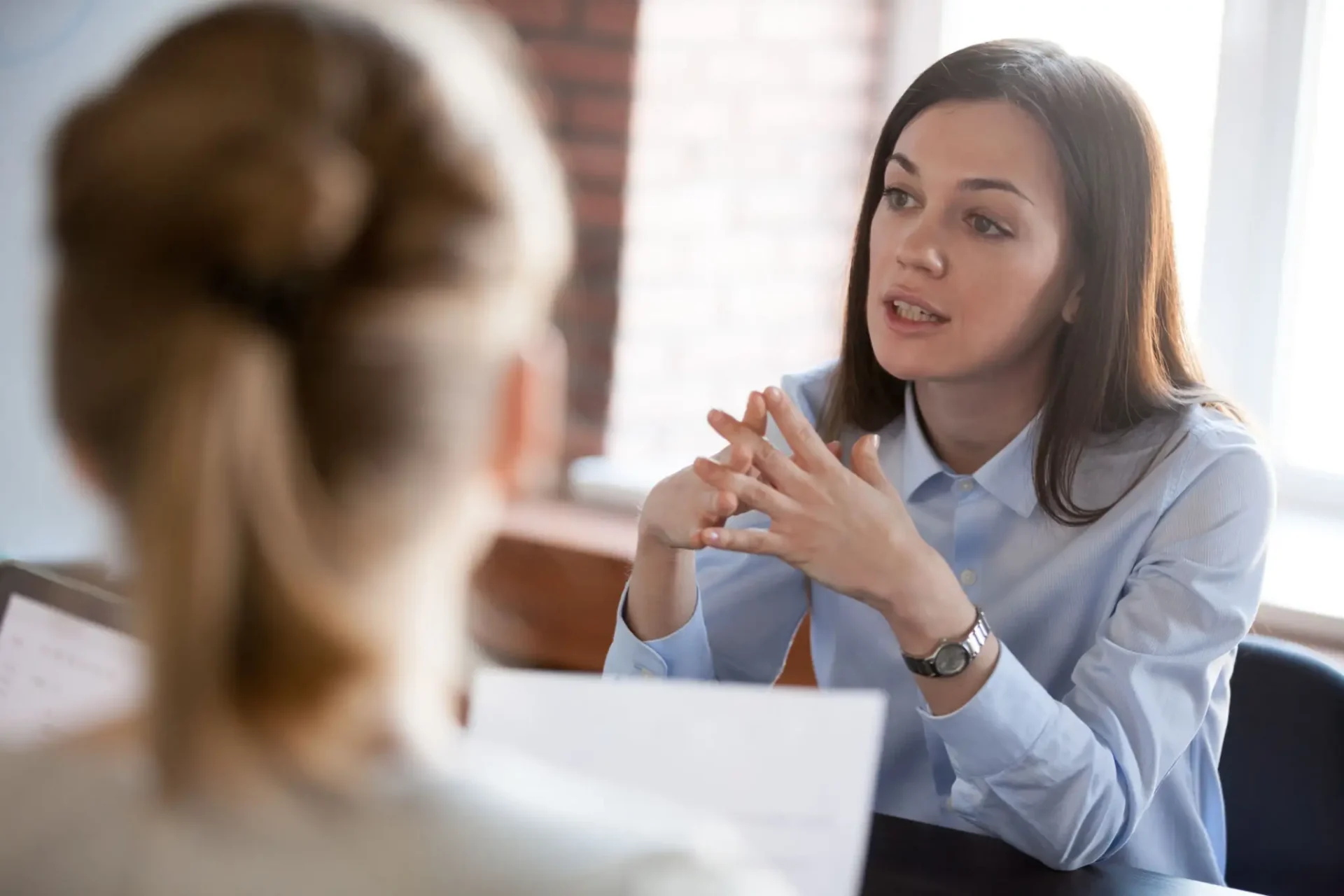 A woman attentively listening and discussing with another person.