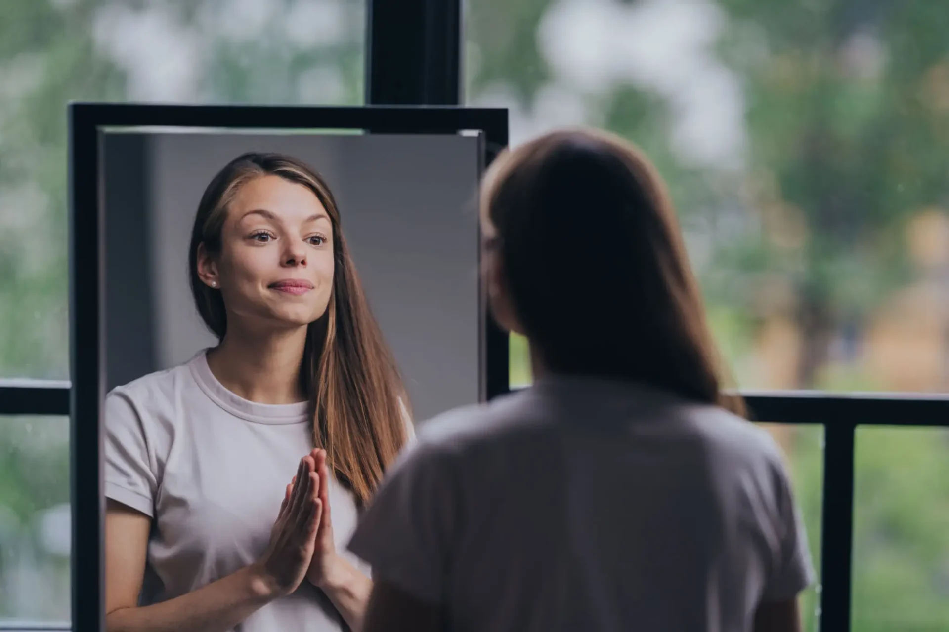 Young woman looking at her reflection in the mirror with a peaceful expression.