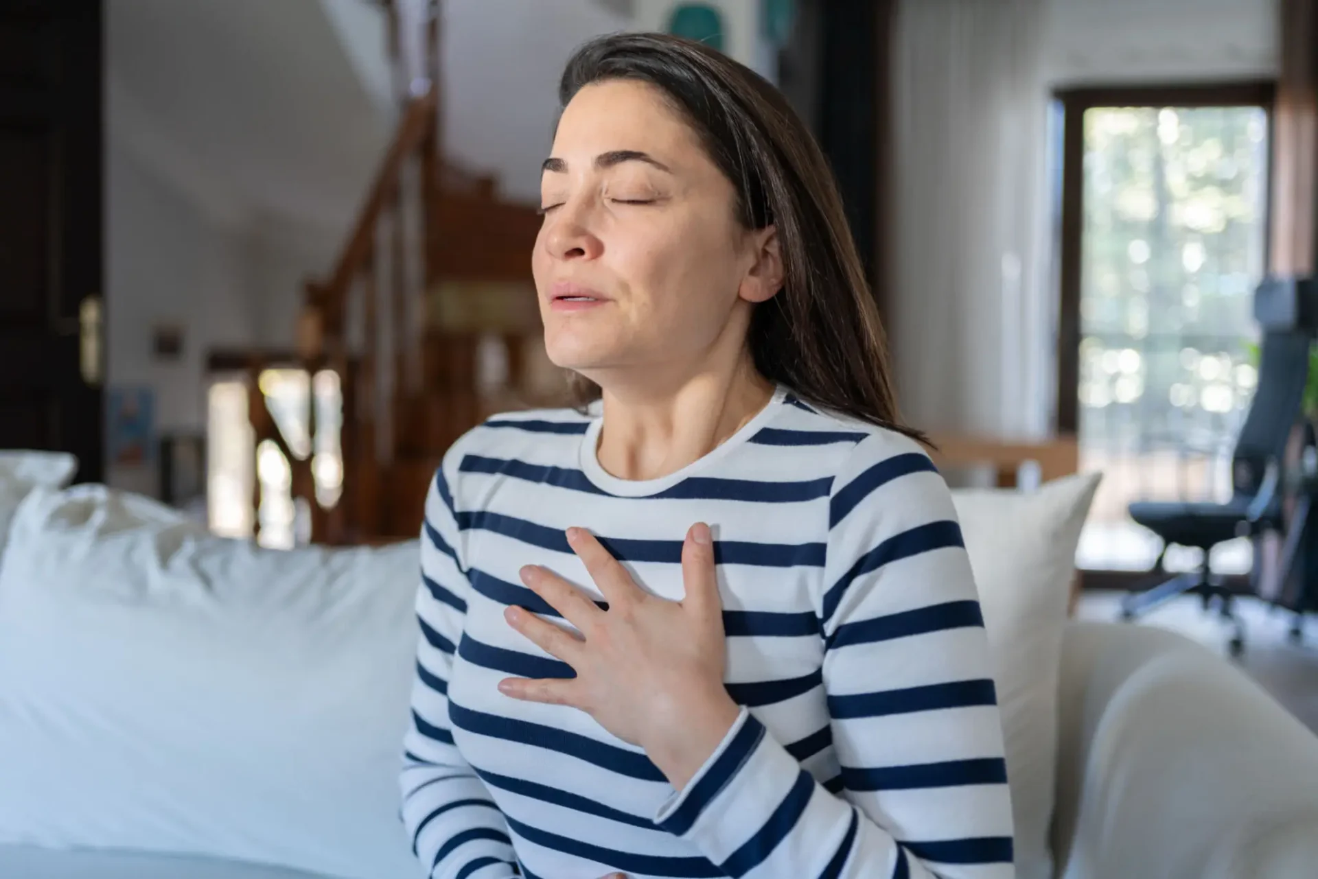 Woman experiencing chest discomfort, possibly indicating pain or anxiety.