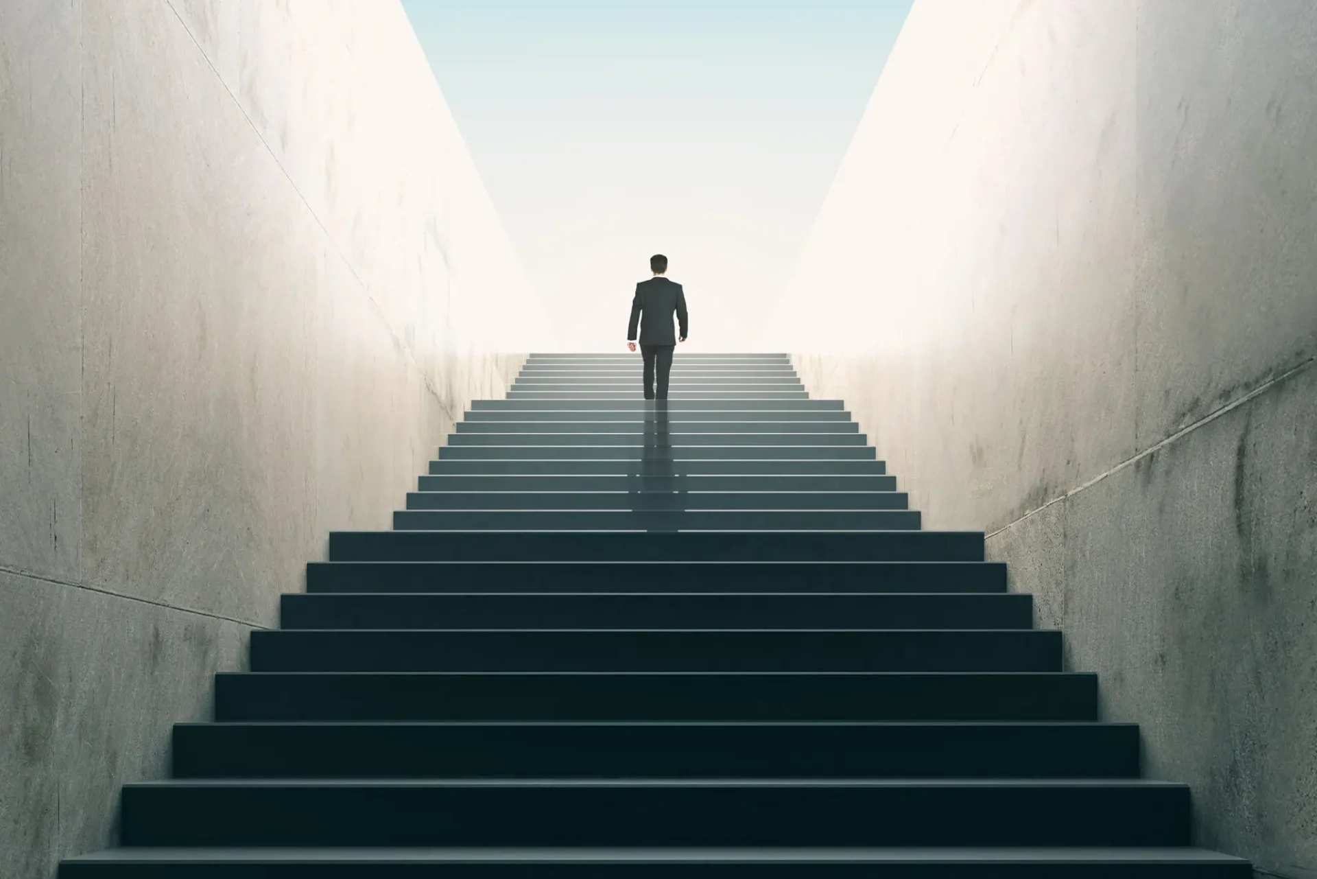 A person walking up a bright staircase surrounded by shadows.