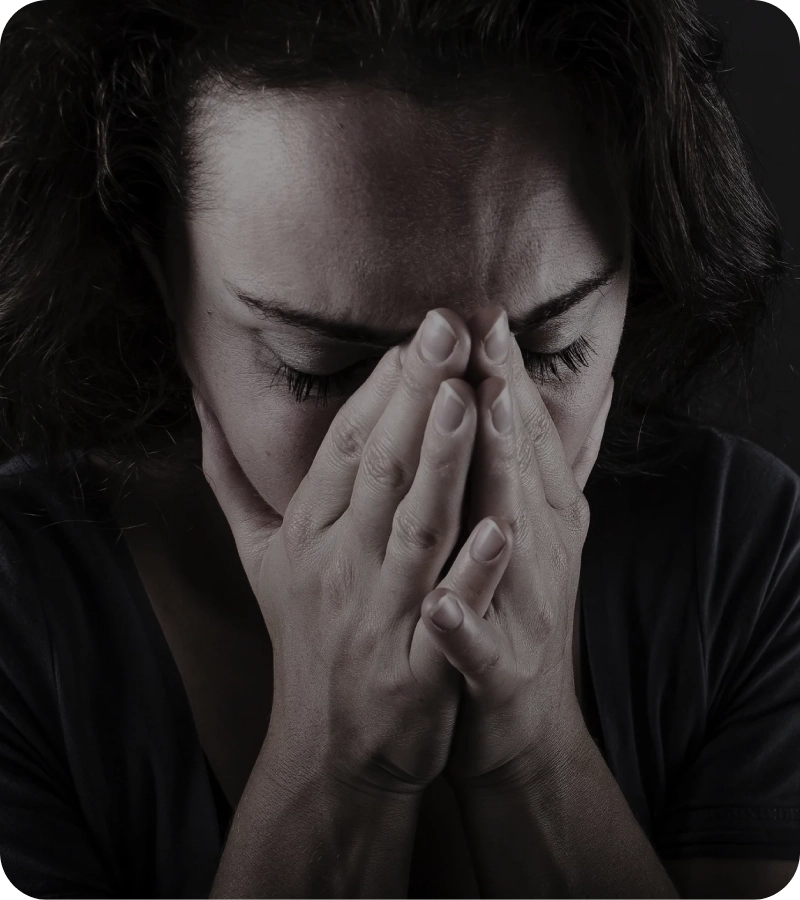A woman covering her face, expressing sadness or distress.