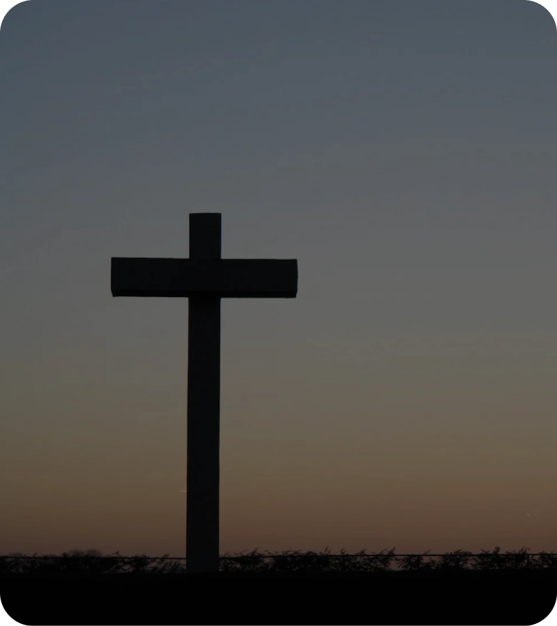 Silhouette of a cross against a dusky sky.